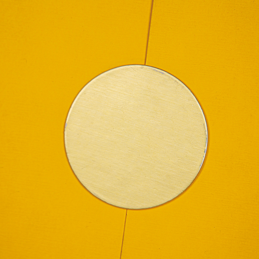 Detail shot of a bespoke gold circular seal on a premium yellow textured gift box.
